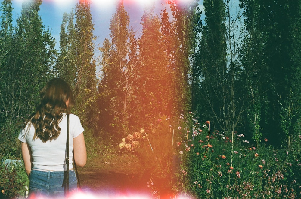 a woman with a gun standing in a forest