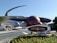 A futuristic attraction featuring large, spherical structures with a metallic appearance, resembling planets with rings. A sign in the foreground reads 'Mission: SPACE' with a logo. Visitors walk towards the entrance under a sunny sky.