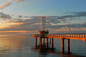 A sleek, modern pier extending over calm water at sunset, highlighting craftsmanship.