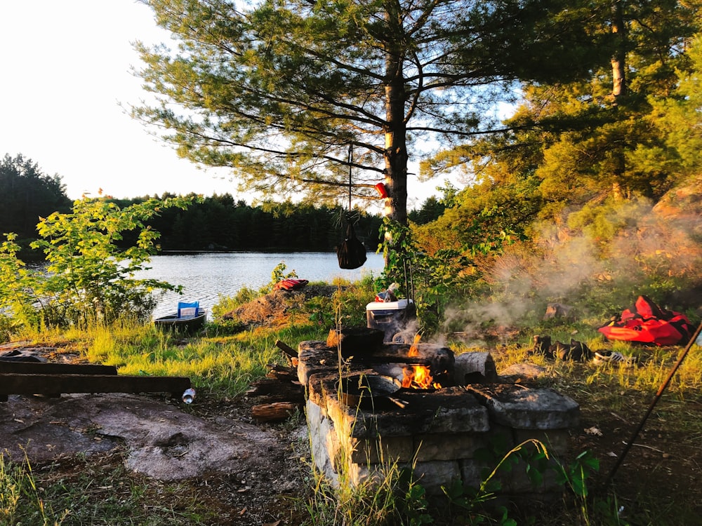 a fire pit in the middle of a field next to a lake