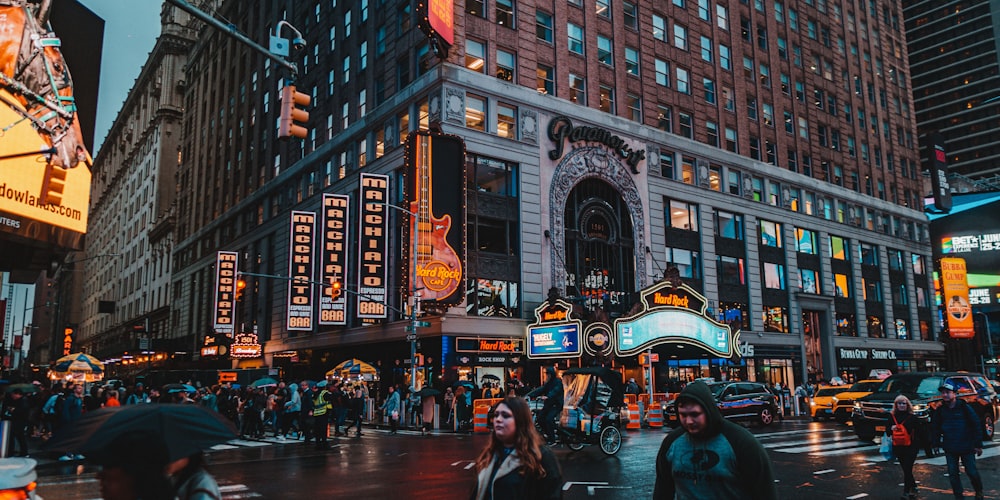 a group of people walking across a street next to tall buildings