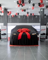 a car covered in a black cloth with a red ribbon