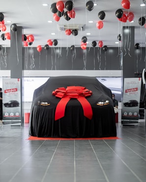 a car covered in a black cloth with a red ribbon