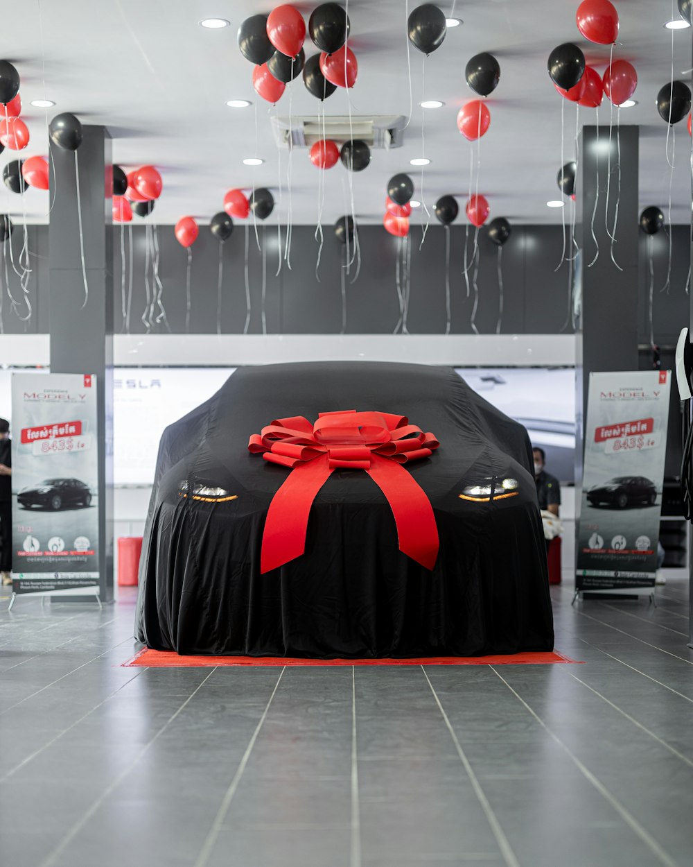 a car covered in a black cloth with a red ribbon