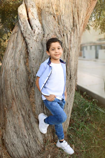 A young boy in a comfortable blue t-shirt and jeans playing outdoors on a sunny day.