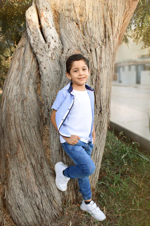 A young boy in a comfortable blue t-shirt and jeans playing outdoors on a sunny day.