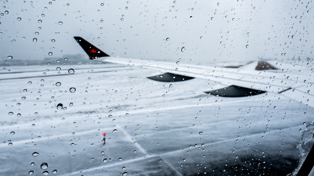 a view of an airplane wing through a rain soaked window