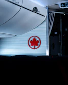 Hands helping a passenger lift luggage into an overhead airplane bin.