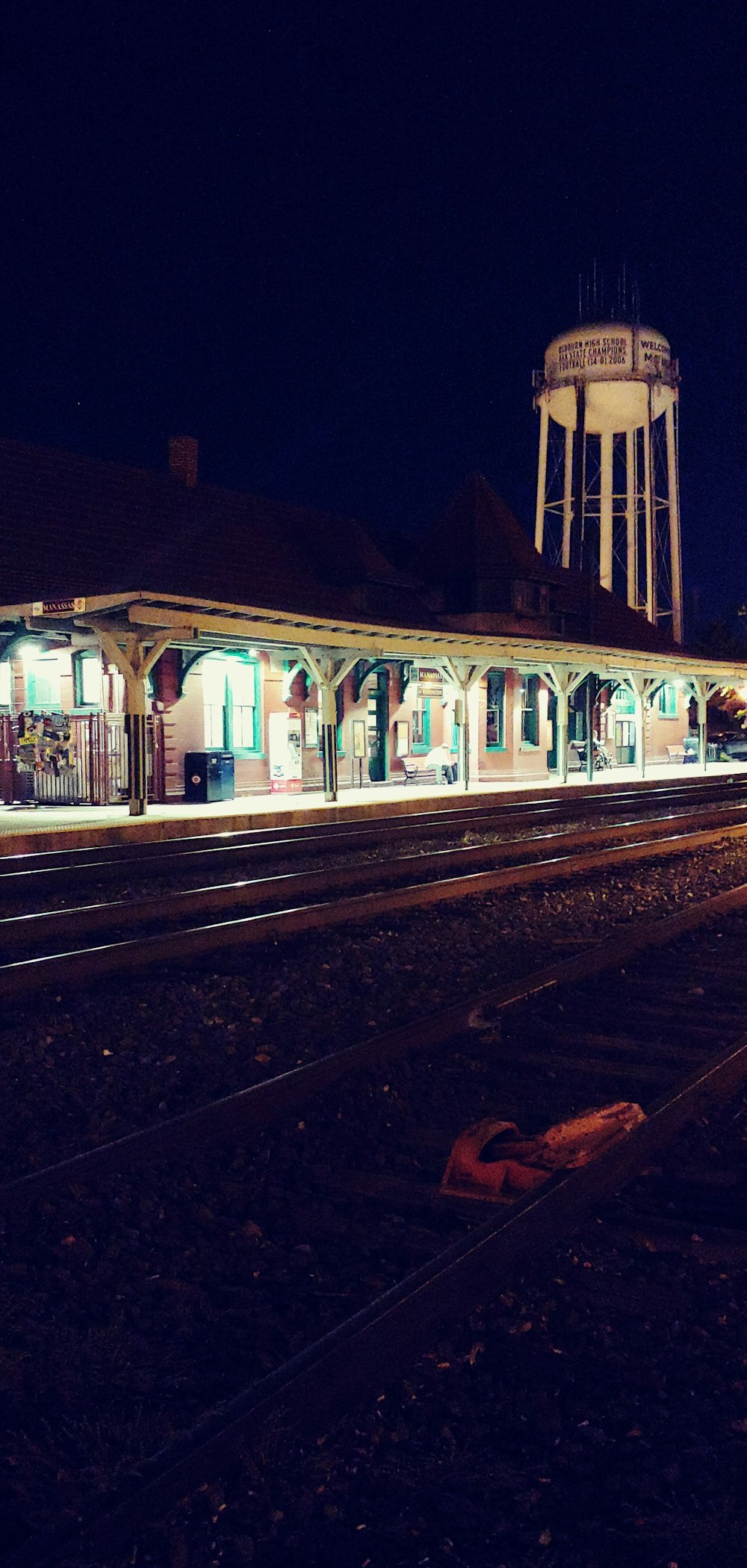 Una estación de tren por la noche con una torre de agua al fondo