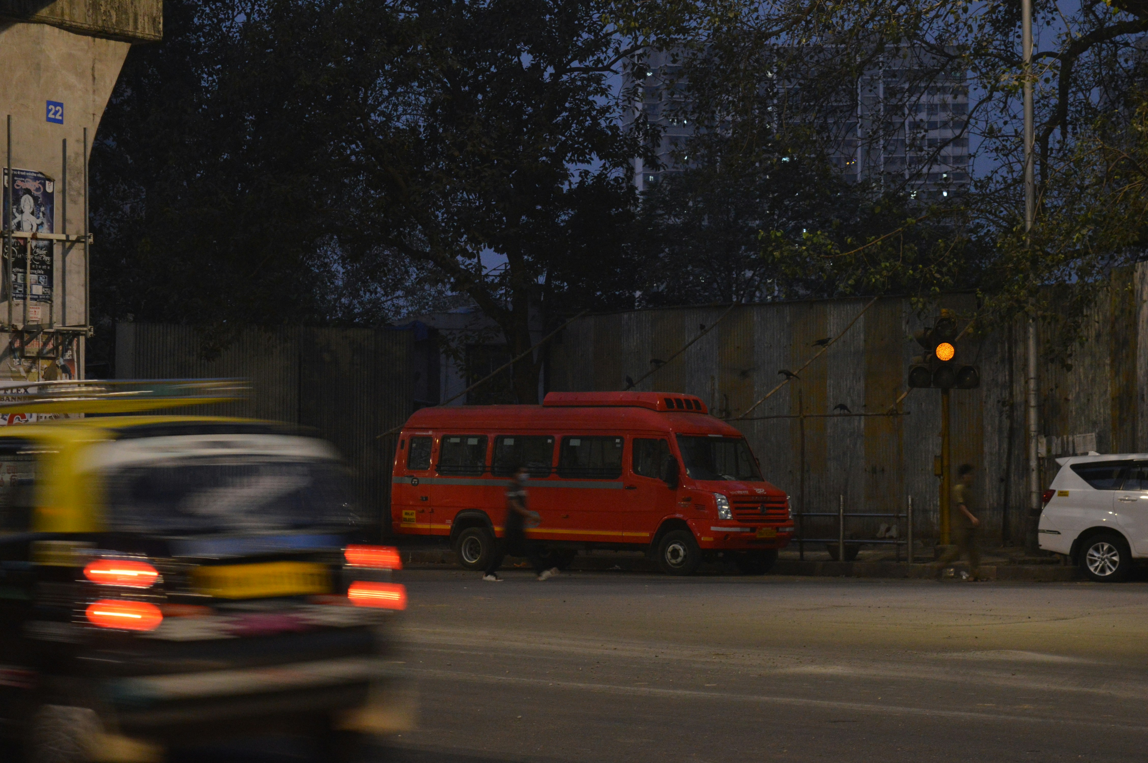 a red van driving down a street next to a tall building