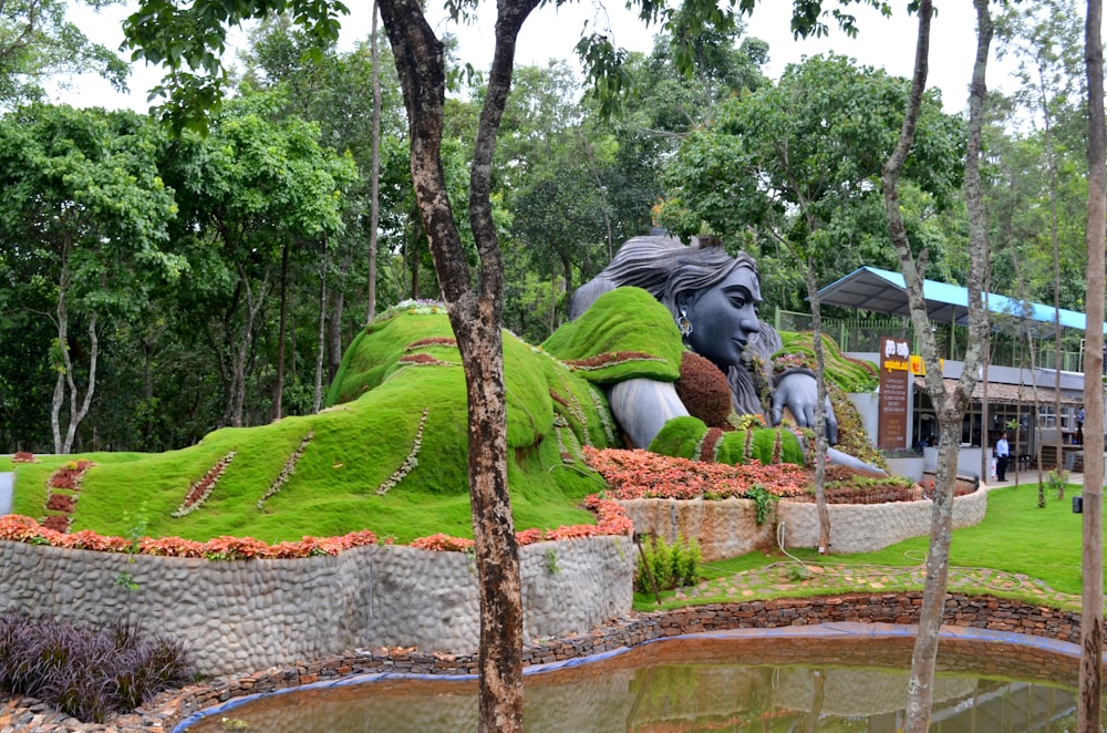 a large statue of a person laying on top of a lush green field