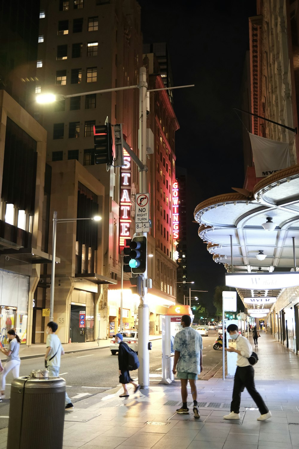 a group of people walking down a street next to tall buildings