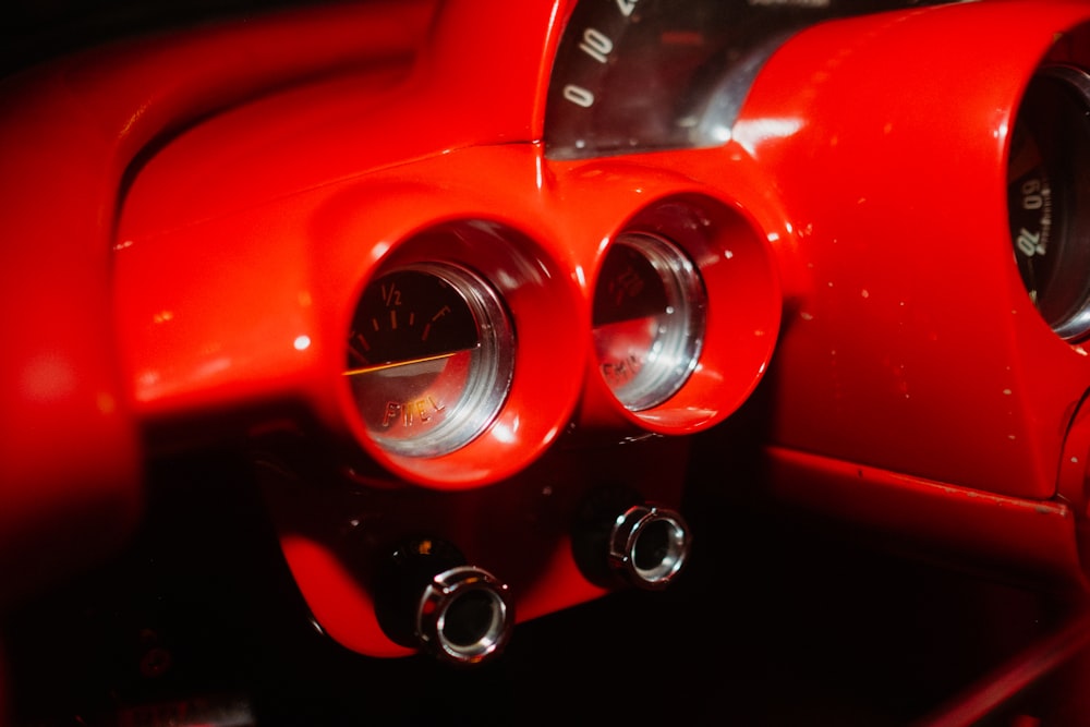 a close up of a red car dashboard with gauges