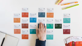 a person's hand on a piece of paper next to a bunch of colored