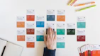 a person's hand on a piece of paper next to a bunch of colored