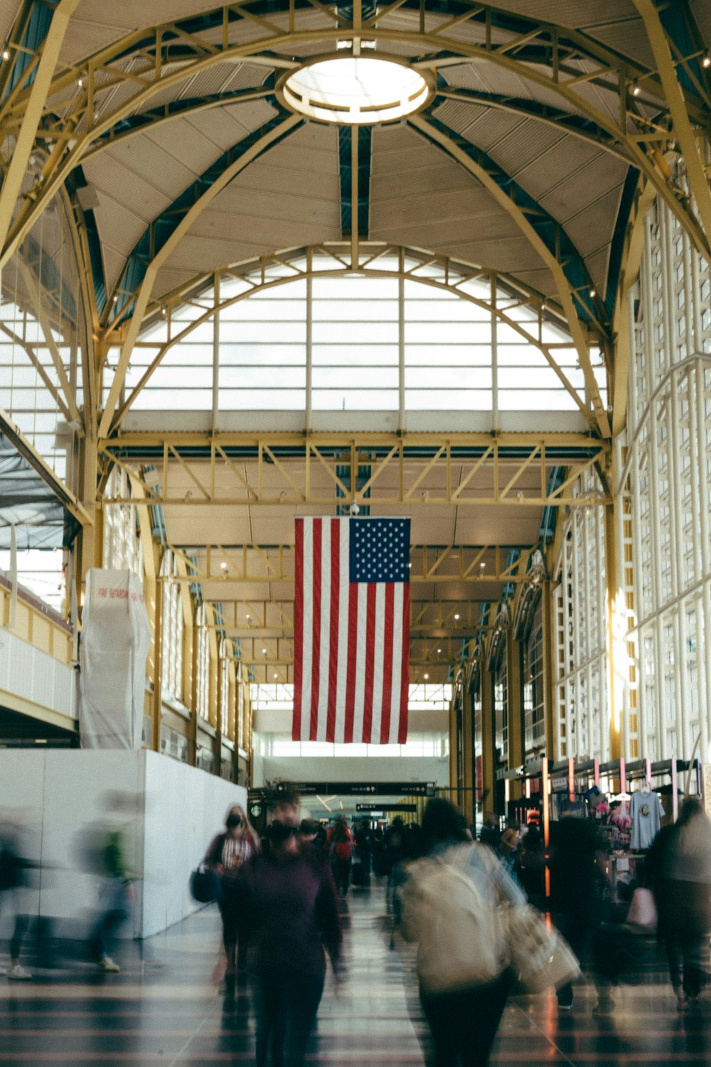a group of people walking down a hall with an american flag hanging from the ceiling