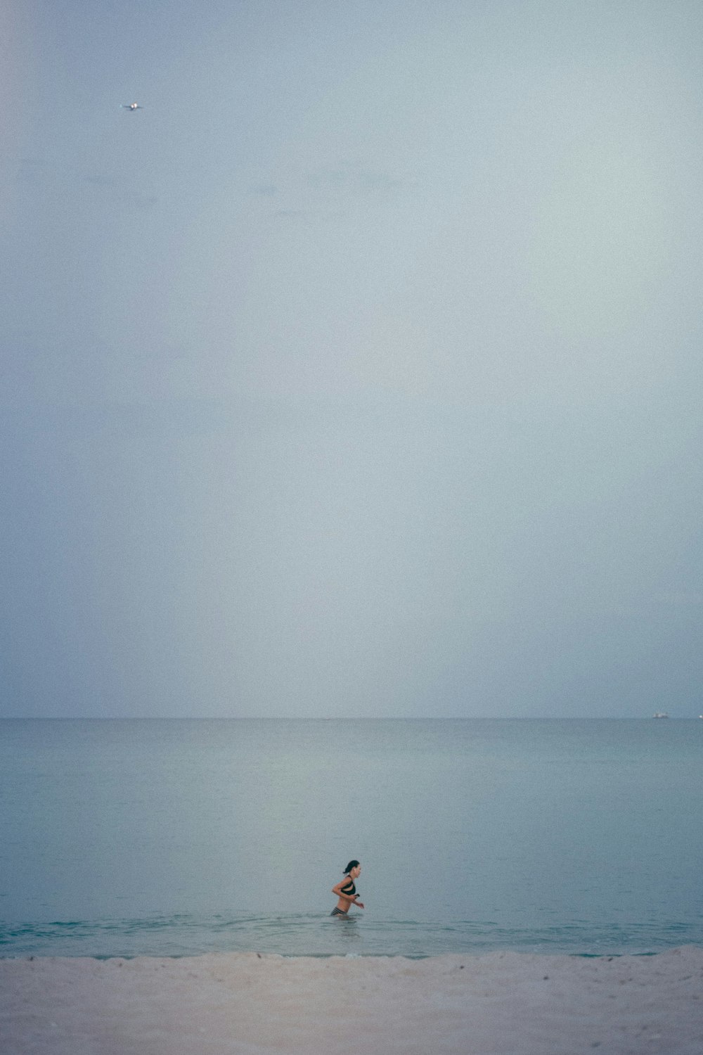 a person wading in the ocean on a cloudy day