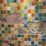 A mosaic wall features two 8-bit style pixel art designs of cartoon animals. The upper design resembles a pink bear with outstretched arms, while the lower depicts a yellow cat with a smiling expression. The background is a colorful arrangement of square tiles in various shades of blue, green, yellow, orange, and pink.