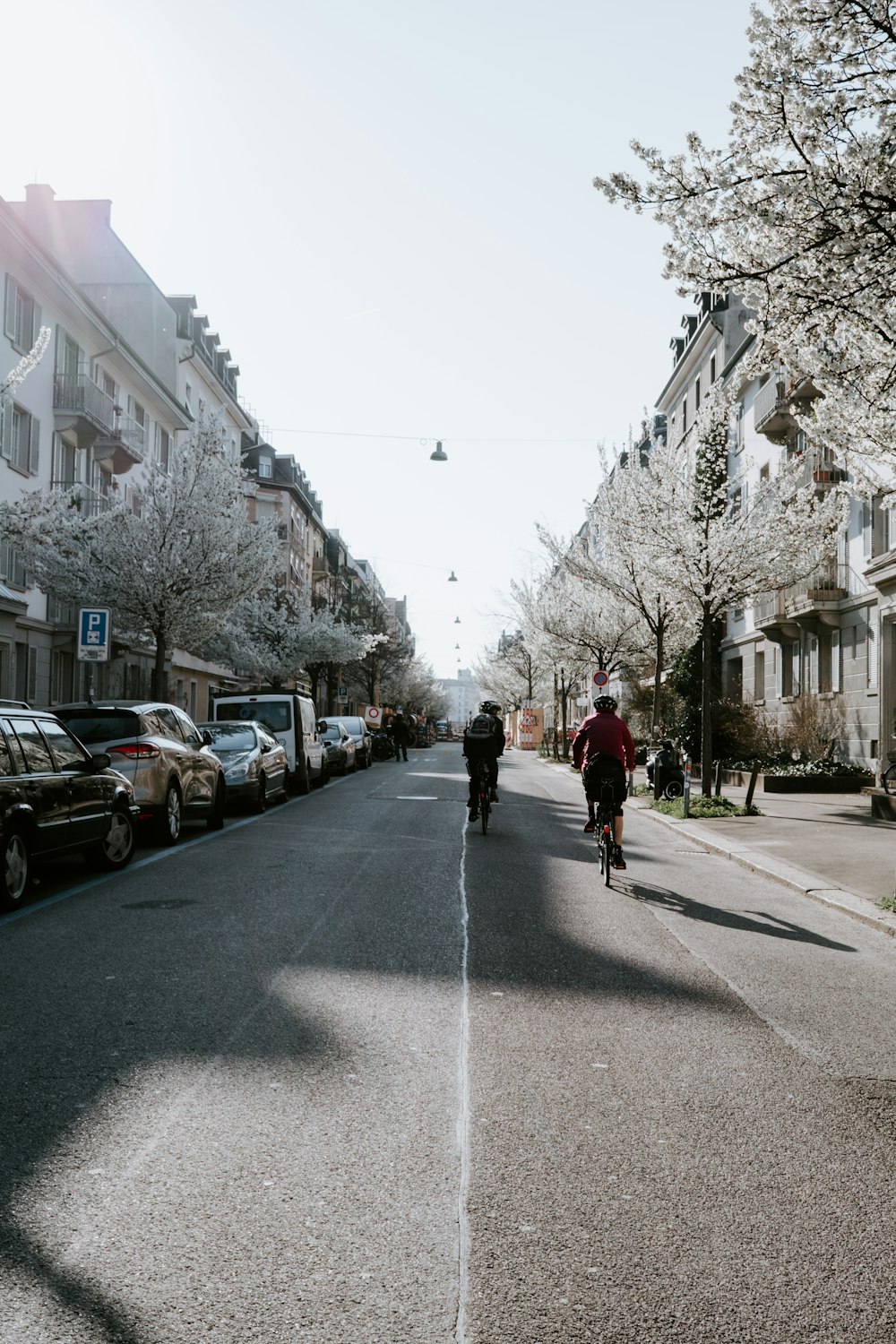 a man riding a bike down a street next to parked cars