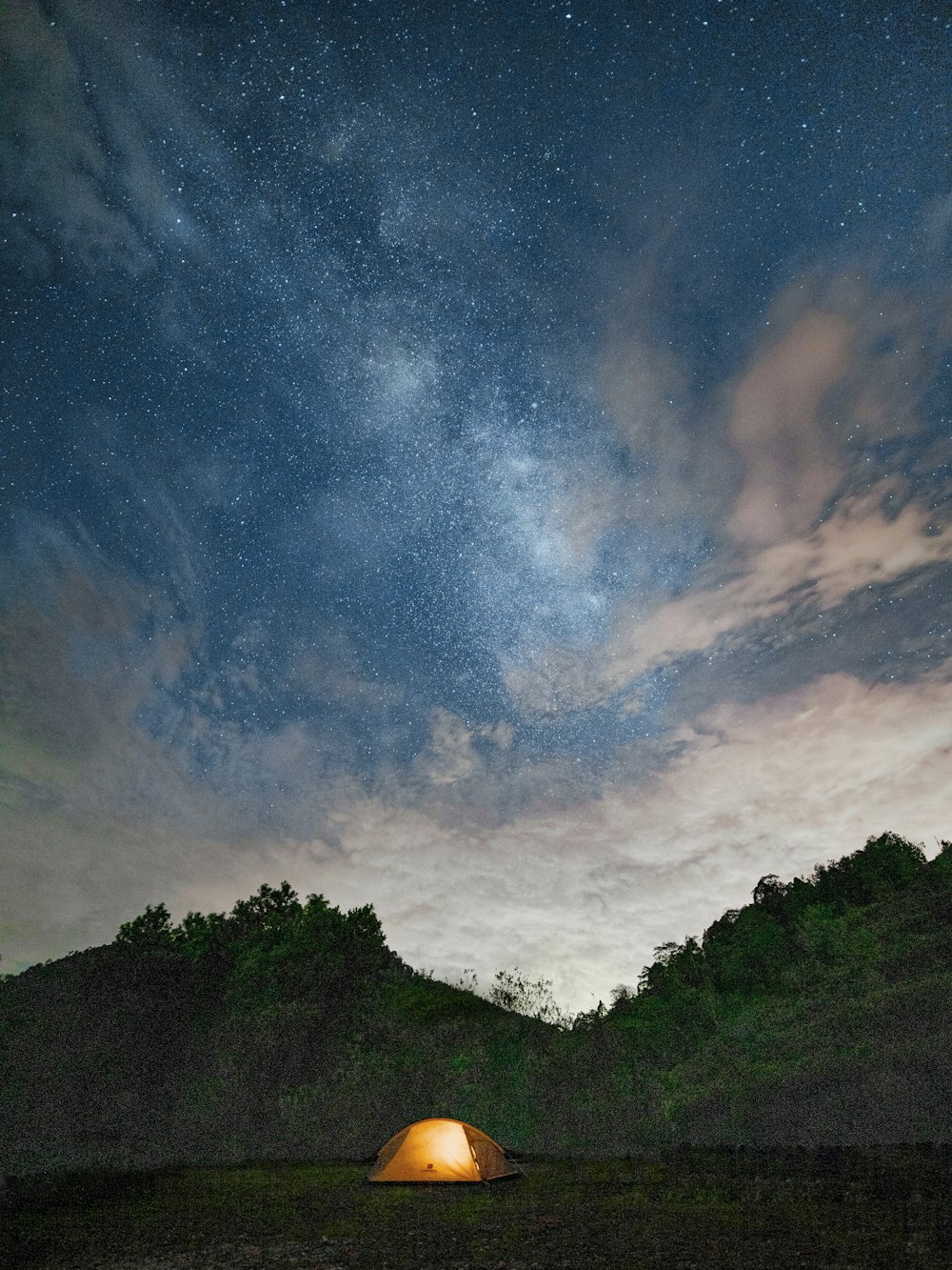 a tent in the middle of a field under a night sky filled with stars