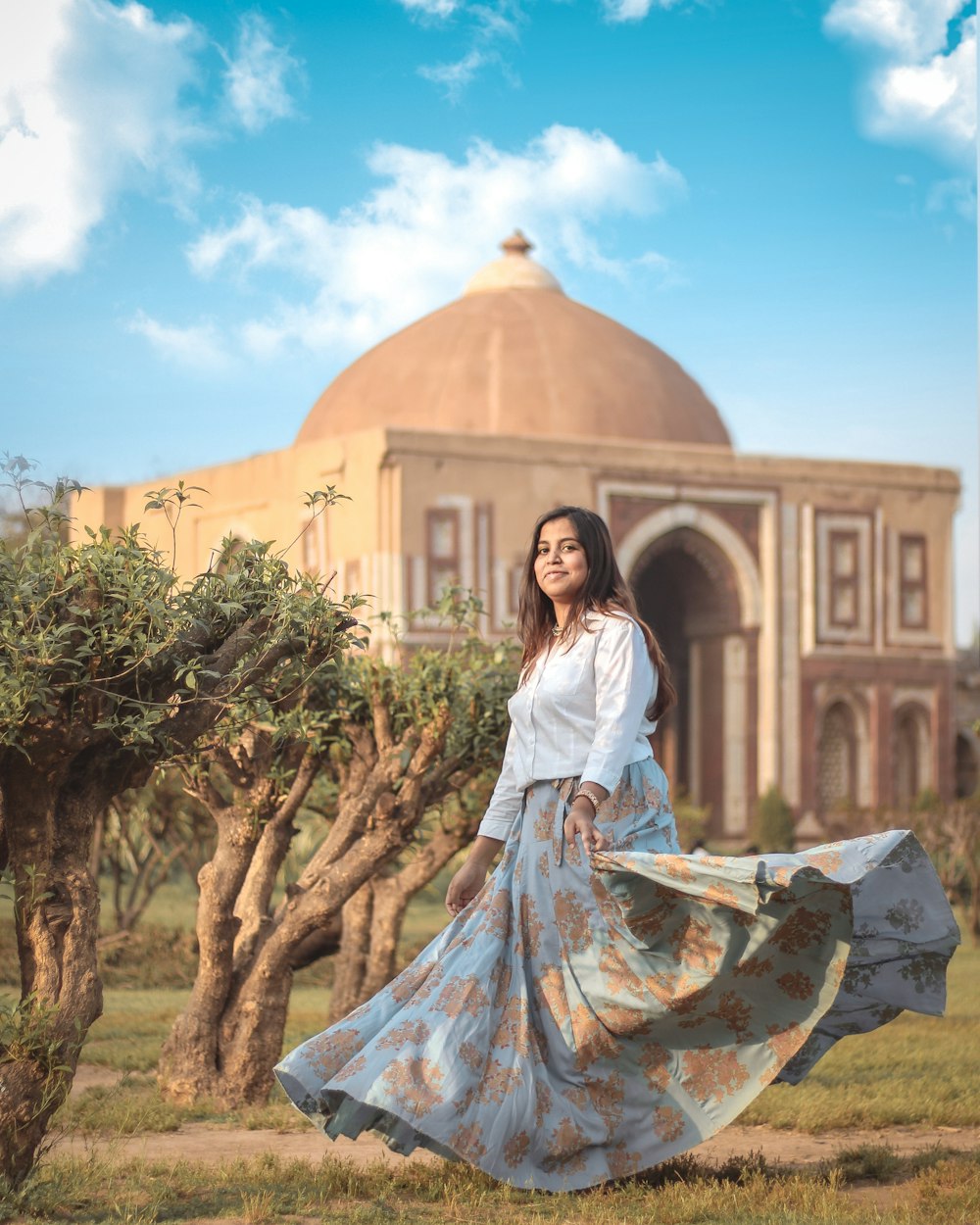 a woman in a long skirt standing in front of a building