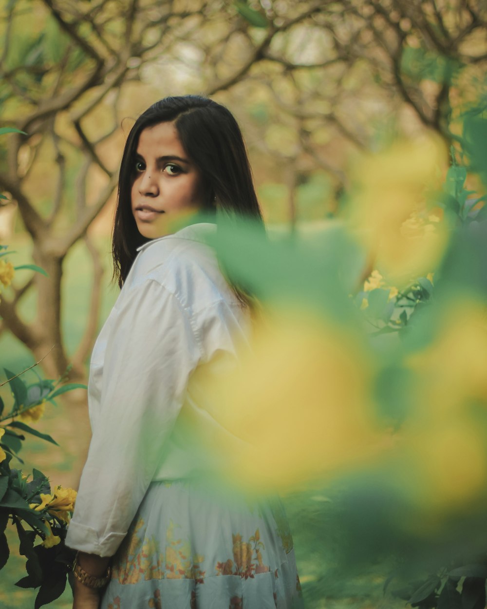 a woman standing in front of a bunch of trees