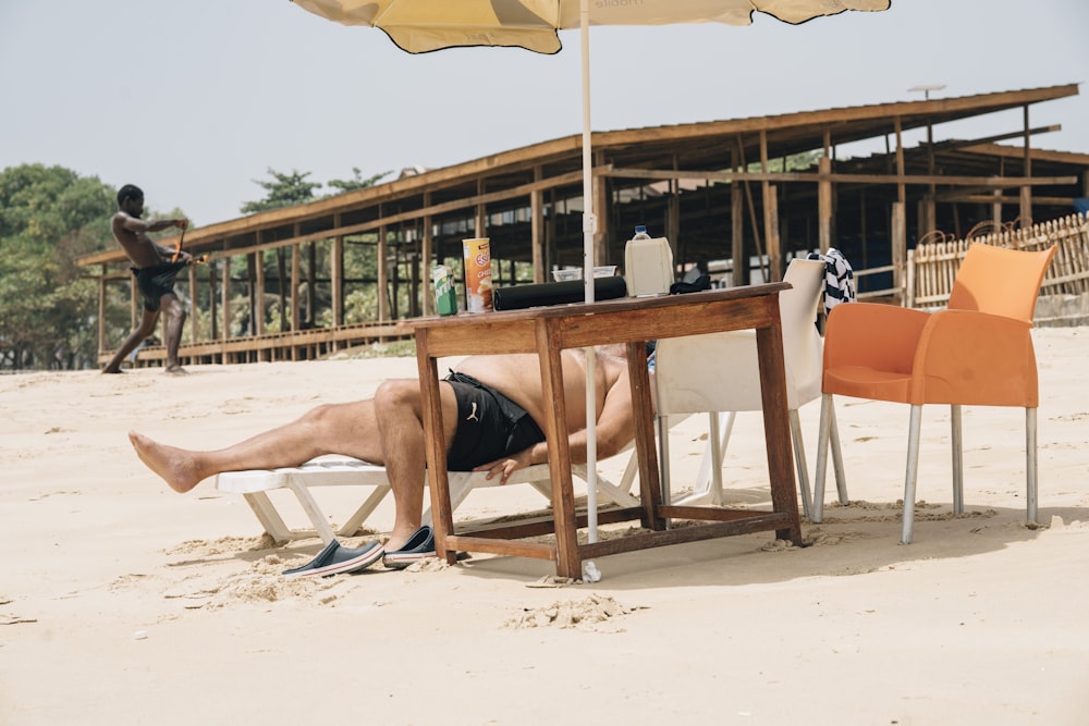 a man laying on the beach under an umbrella