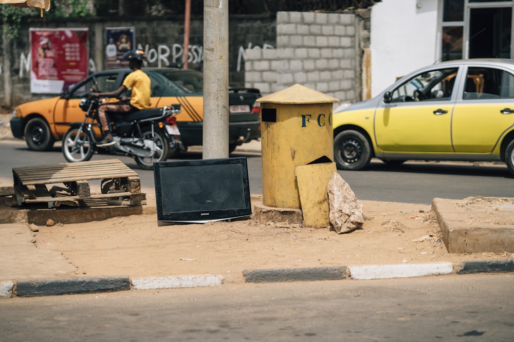 a tv sitting on the side of a road next to a trash can