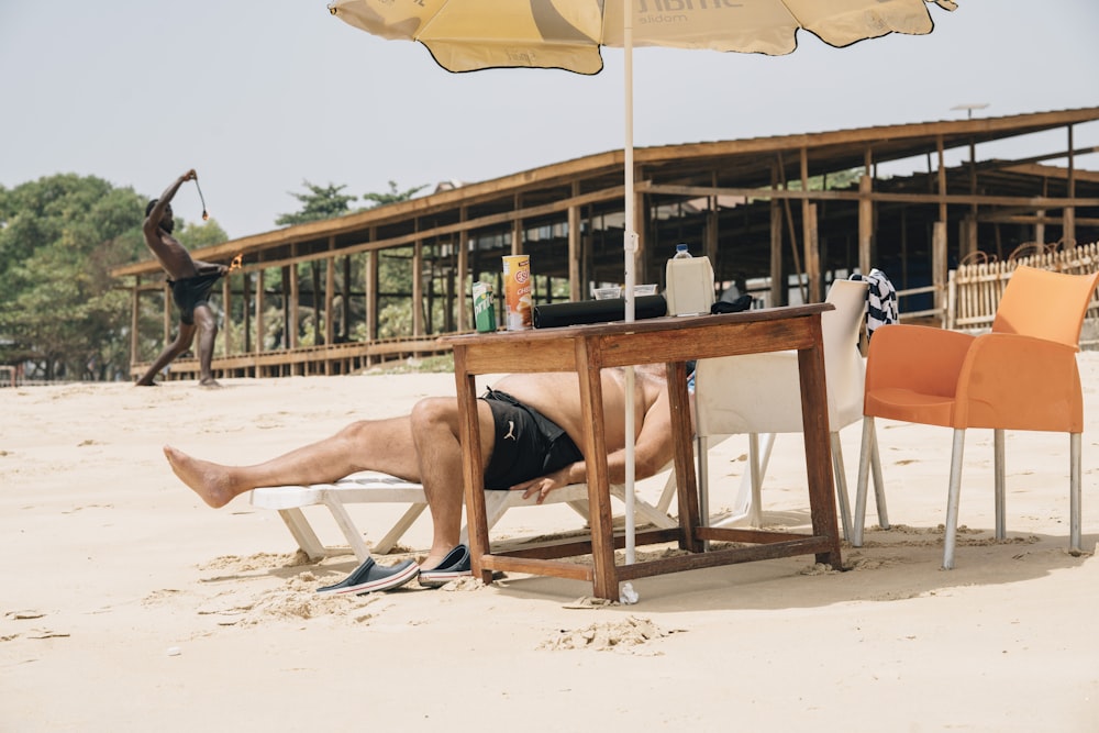 a man laying on the beach under an umbrella