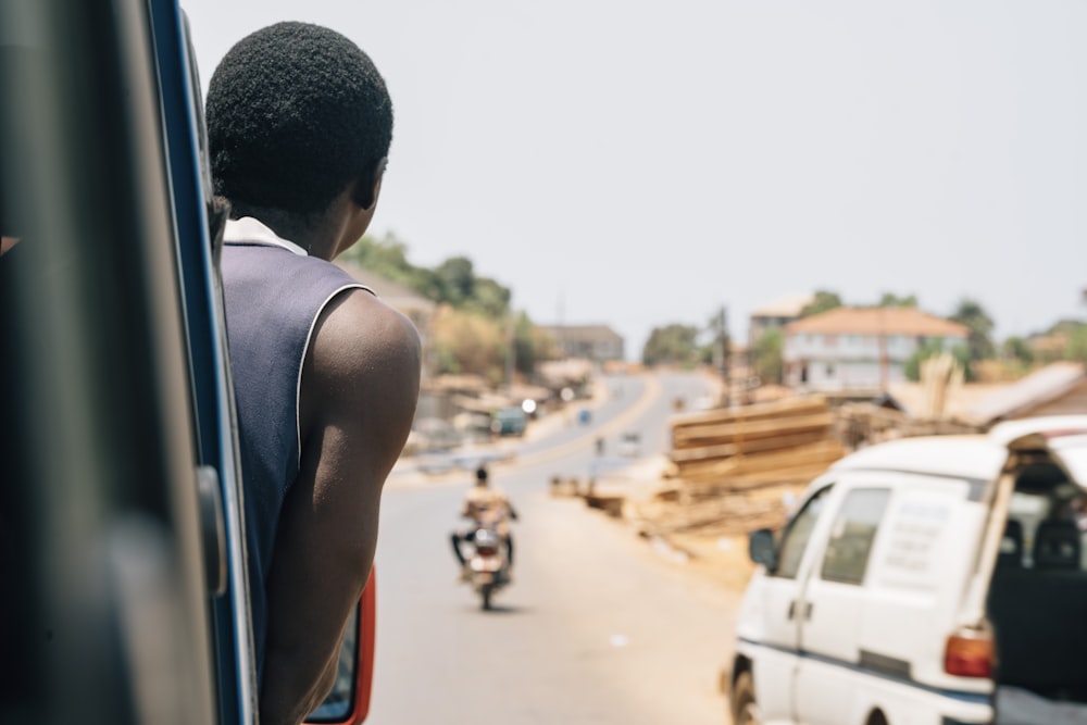 a man riding a bus down a street next to a white van