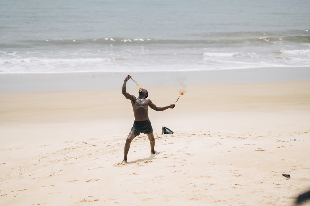 Un uomo che tiene una mazza da baseball in cima a una spiaggia sabbiosa