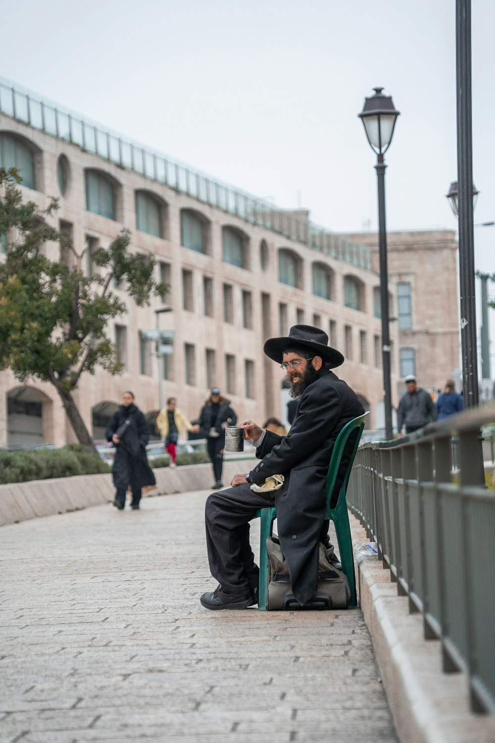 a man sitting on a green chair on a sidewalk