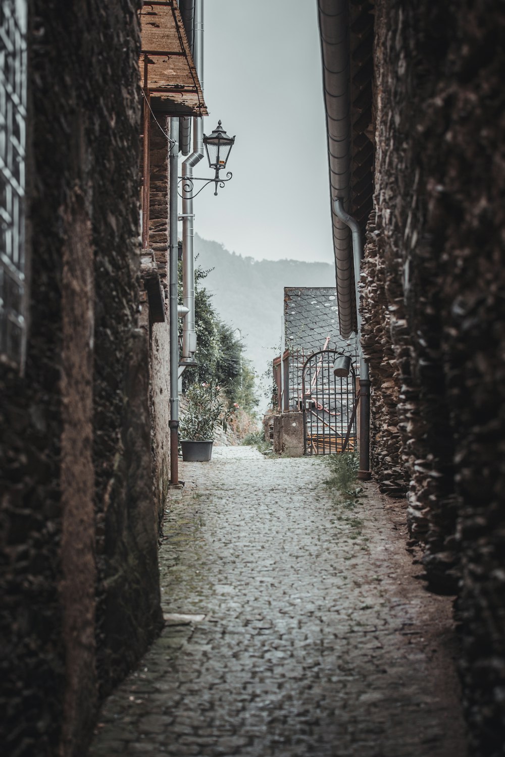 a cobblestone street with a lantern hanging from the side of it