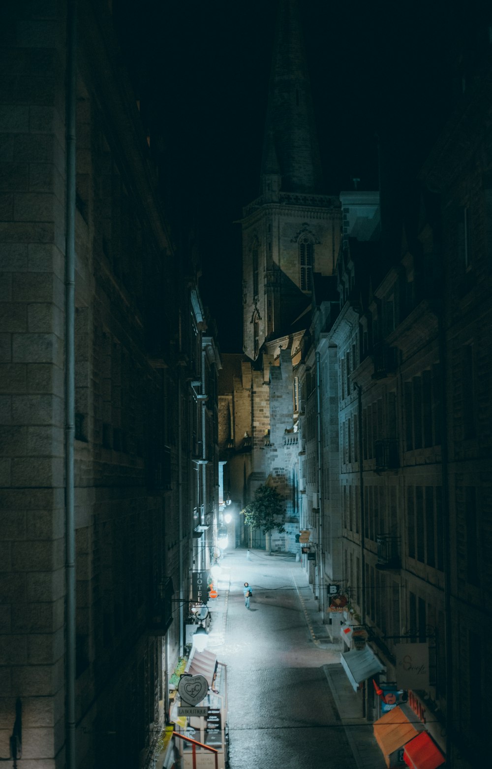 a dark alley with a clock tower in the background