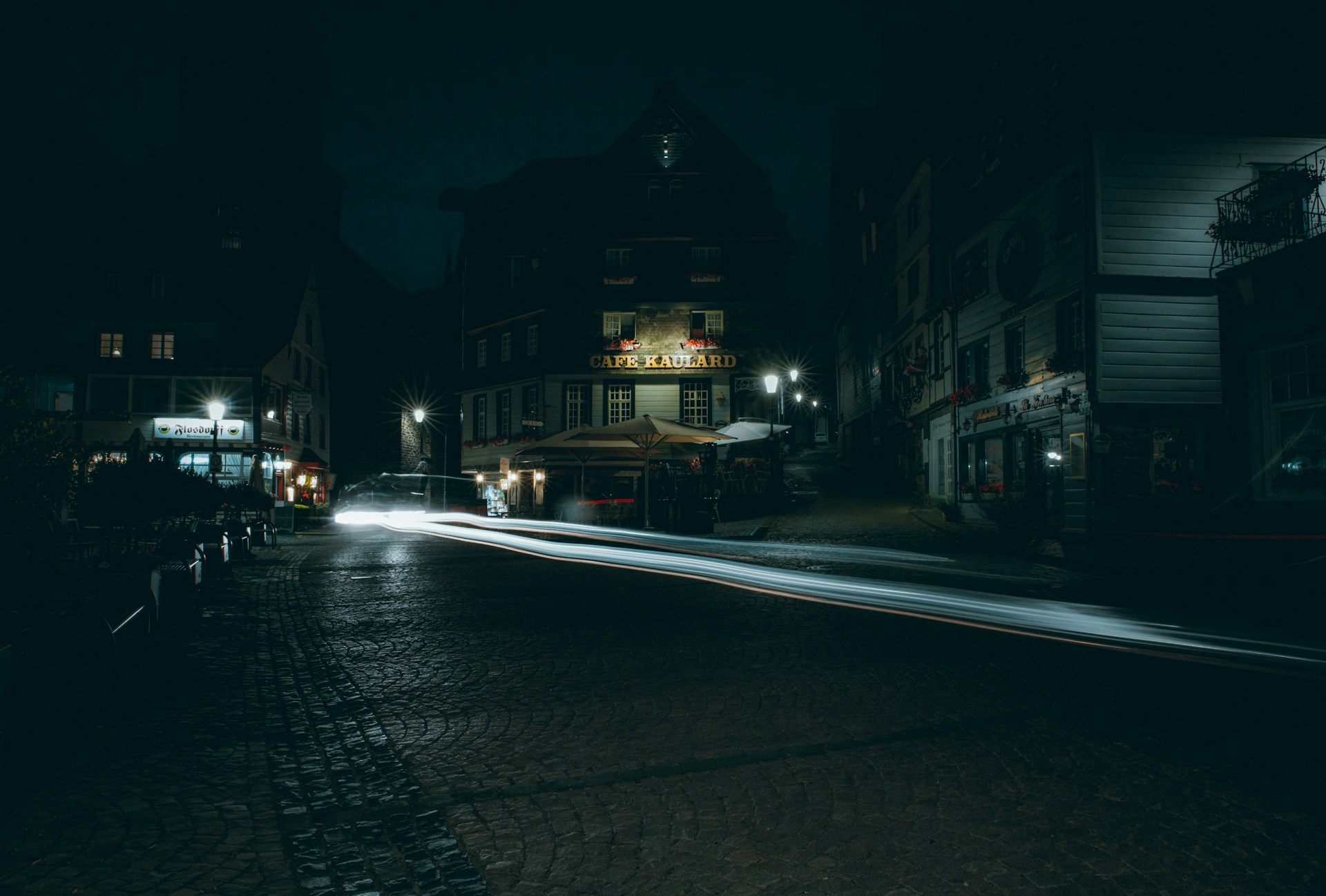 a street at night with a car passing by