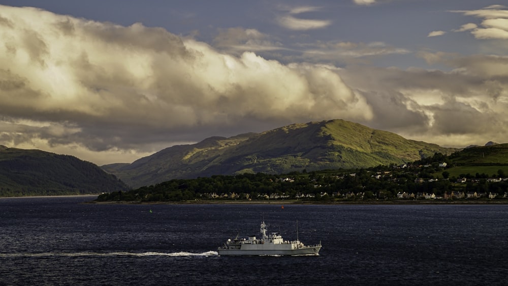 a boat is sailing in the water near a mountain range