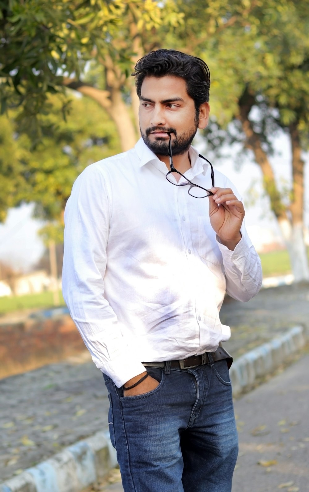 a man in a white shirt is holding a pair of glasses