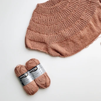 Cozy handmade knitted scarf in warm brown tones, laid out on a rustic wooden table.