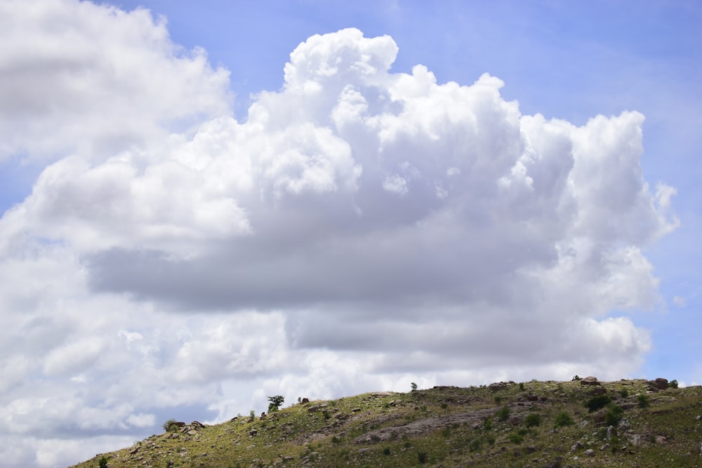 a large cloud is in the sky over a hill