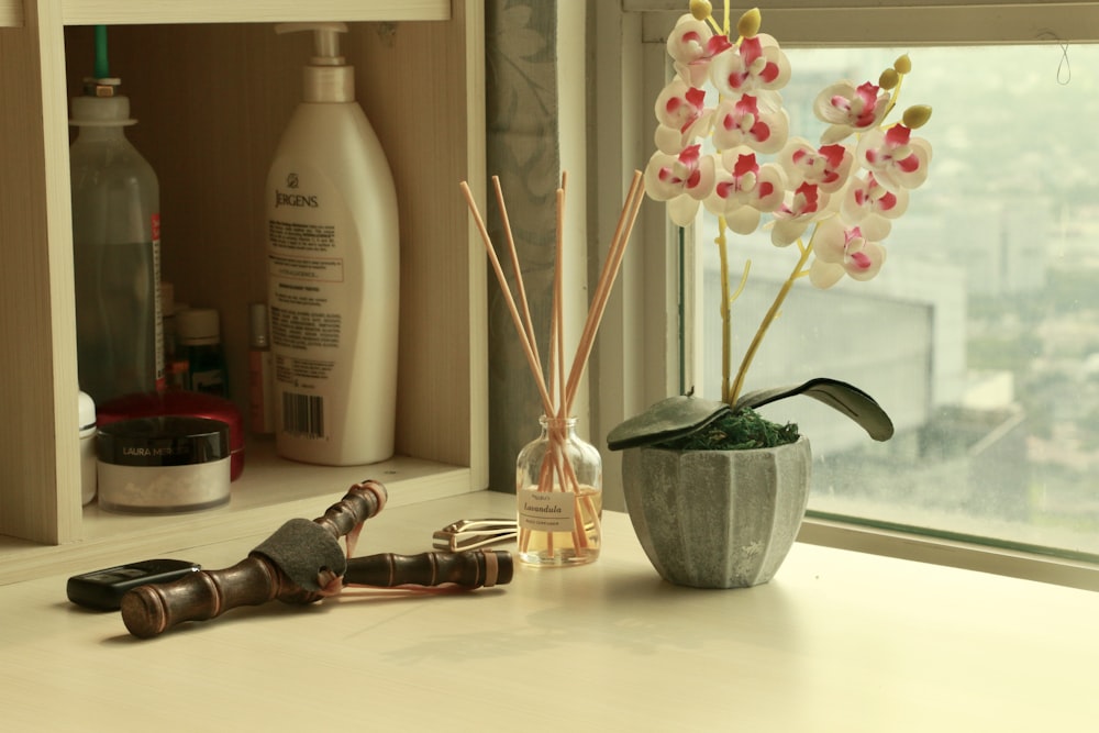 a window sill with a vase of flowers and a pair of scissors