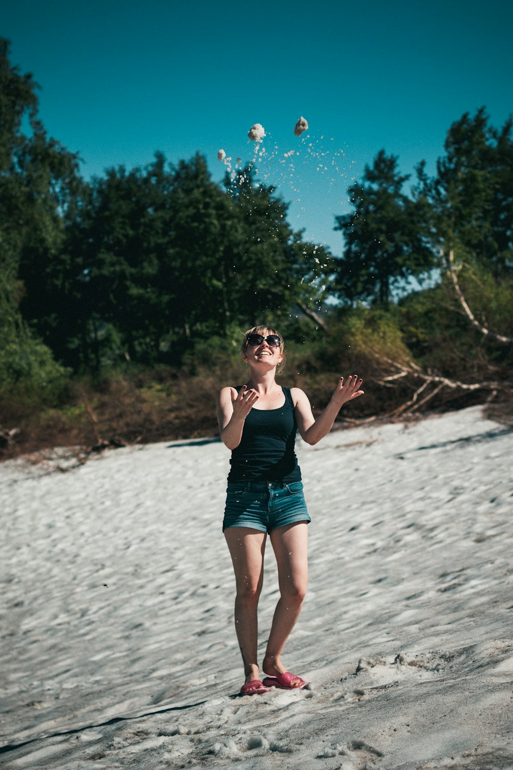 a woman standing on a beach flying a kite