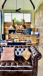 a brown leather couch sitting in a living room next to a kitchen
