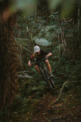 A mountain biker riding through a lush forest trail in Minas Gerais.