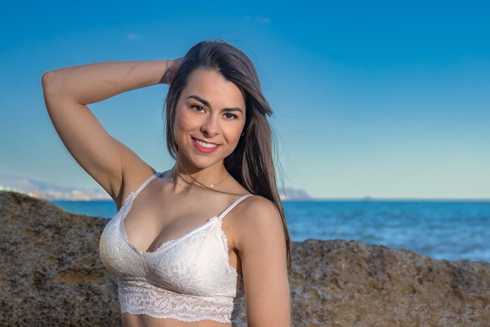 a beautiful woman in a white bikini posing by the ocean
