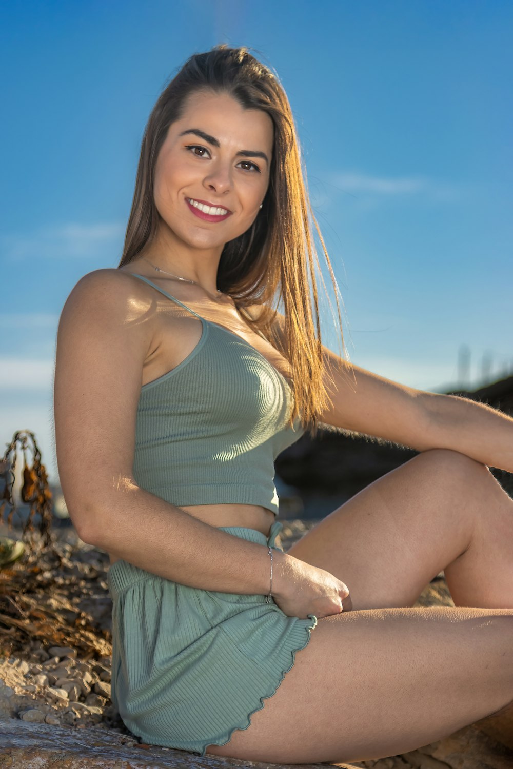 a beautiful young woman sitting on top of a rock