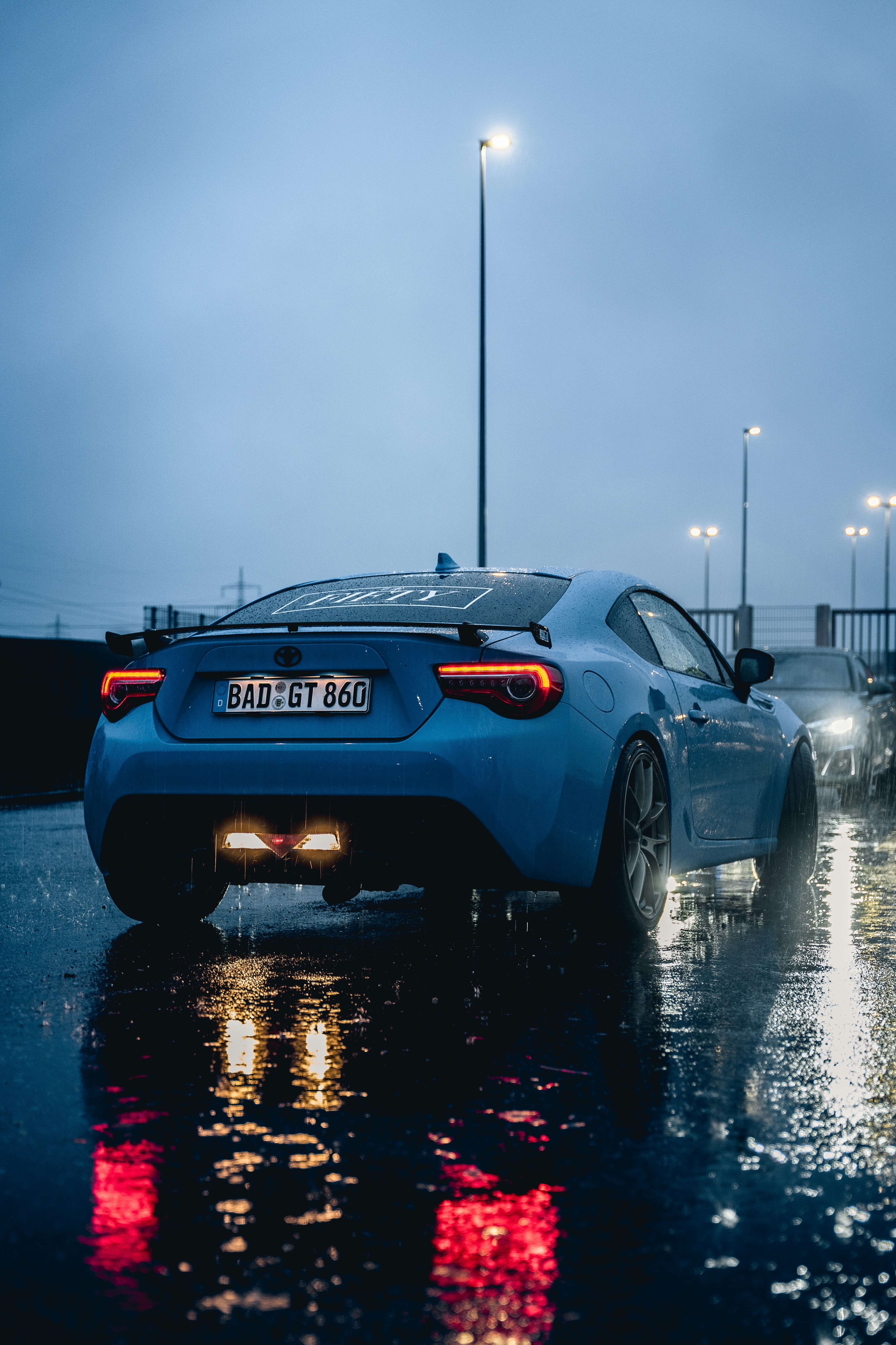a blue sports car driving down a wet road