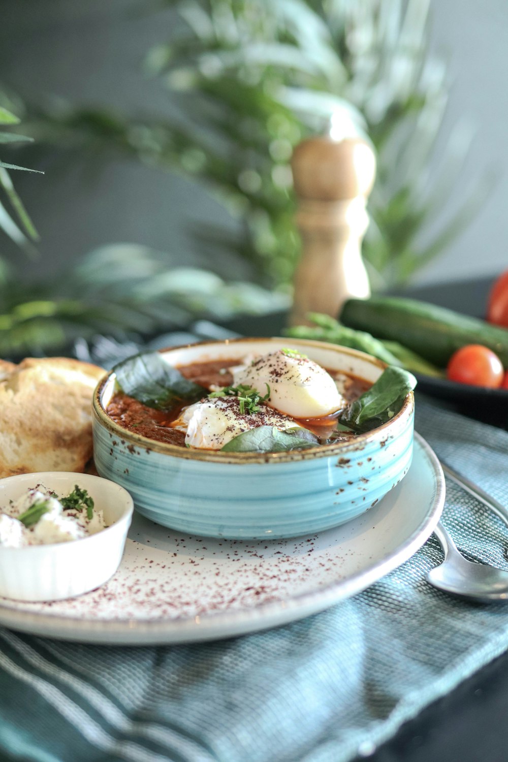 a bowl of soup on a plate with bread and vegetables