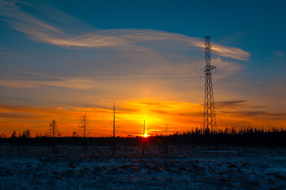 the sun is setting over a snowy field