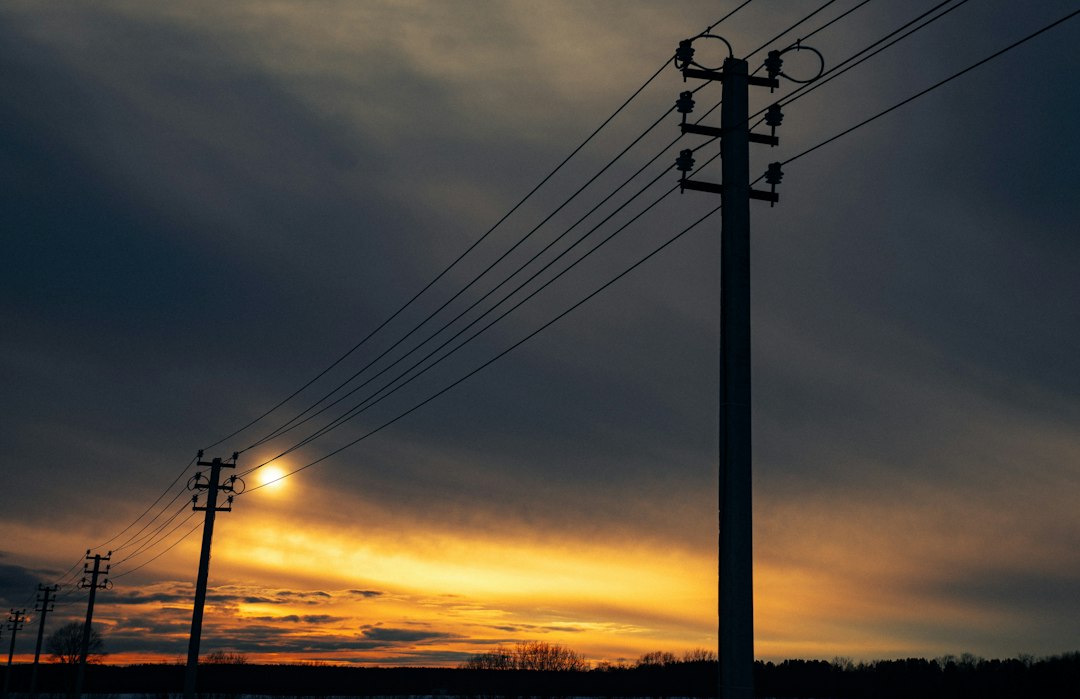 the sun is setting behind power lines and telephone poles