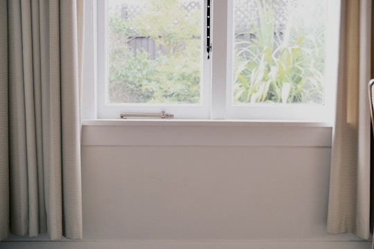 A professional installer fitting a window in a bright room.